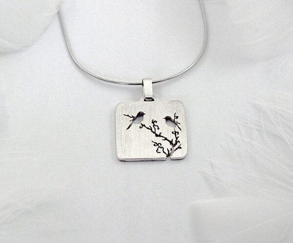 Magpie on the Plum The silver necklace of "Magpie on the Plum" shows a blooming plum branch and a flying magpie, symbolizing happiness and good luck, reflecting the Chinese flower and bird culture