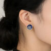 Close-up of a model wearing the Winter Spirit snowflake earrings. The frosted enamel design complements a cozy winter look, showing the elegant scale and artistic detail of the jewelry.