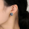Close-up of a model wearing the Winter Spirit snowflake earrings. The frosted enamel design complements a cozy winter look, showing the elegant scale and artistic detail of the jewelry.