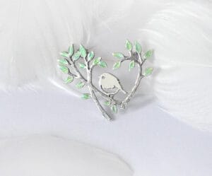The silver enamel brooch “Spring Warmth” shows several early orioles competing for warmth in the trees, reflecting the vitality and vigor of spring