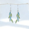A pair of delicate leaf-shaped earrings featuring translucent willow-green enamel using the Plique-à-jour technique. The silver-framed enamel mimics the glow of sunlit spring leaves.