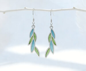 A pair of delicate leaf-shaped earrings featuring translucent willow-green enamel using the Plique-à-jour technique. The silver-framed enamel mimics the glow of sunlit spring leaves.