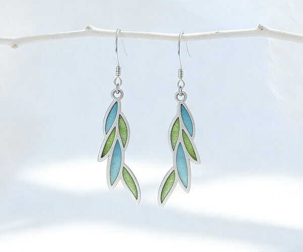 A pair of delicate leaf-shaped earrings featuring translucent willow-green enamel using the Plique-à-jour technique. The silver-framed enamel mimics the glow of sunlit spring leaves.