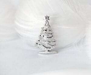 The silver Christmas tree brooch is topped with stars and decorated with snowflakes, showing the festive mood and magic of winter.