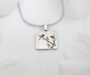 The silver necklace of "Magpie on the Plum" shows a blooming plum branch and a flying magpie, symbolizing happiness and good luck, reflecting the Chinese flower and bird culture