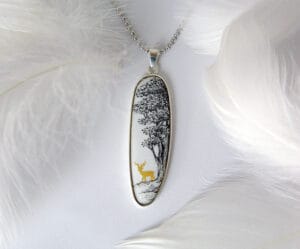 A hand-painted enamel necklace depicting a tranquil deer in a quiet hideaway under the shade of a tree beside a stream, showcasing natural elegance and tranquility, perfect for everyday wear or special occasions.