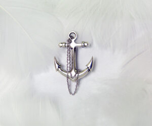 Cross anchor-shaped 925 sterling silver brooch, featuring a delicate design with a dangling silver chain. The polished finish exudes elegance and a stylish nautical theme accessory.