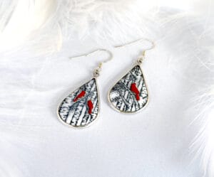 Winter Melody hand-painted enamel earrings, teardrop-shaped asymmetric design featuring a winter scene with poplar trees and red birds, symbolizing the intertwined warmth and cold of a love song.