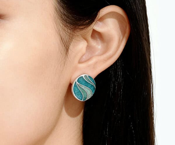 Close-up shot of a model wearing the "Still Waters Run Deep" blue and green Champlevé Enamel 925 silver earrings, highlighting the tranquil, flowing color design.