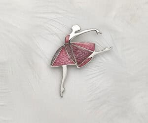 Close-up of the "Dancing Moments" Champlevé Enamel 925 silver ballerina brooch against a white feather background. Features a geometric pink-lavender translucent enamel skirt with visible chiseled texture.