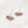 Poppy Grace Plique-à-jour enamel earrings in 925 sterling silver, featuring a delicate pink ginkgo-shaped fan design suspended on long silver chains, set against a blurry spring meadow background with soft sunlight.